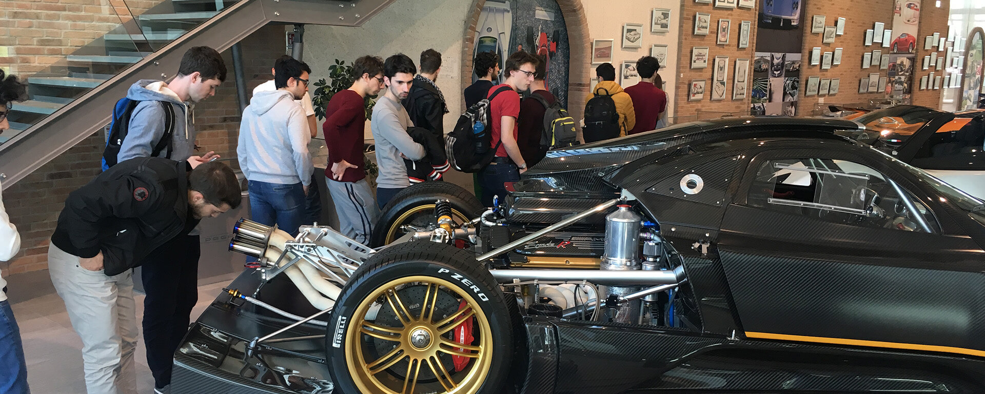 Students visiting the Pagani museum observing a race car