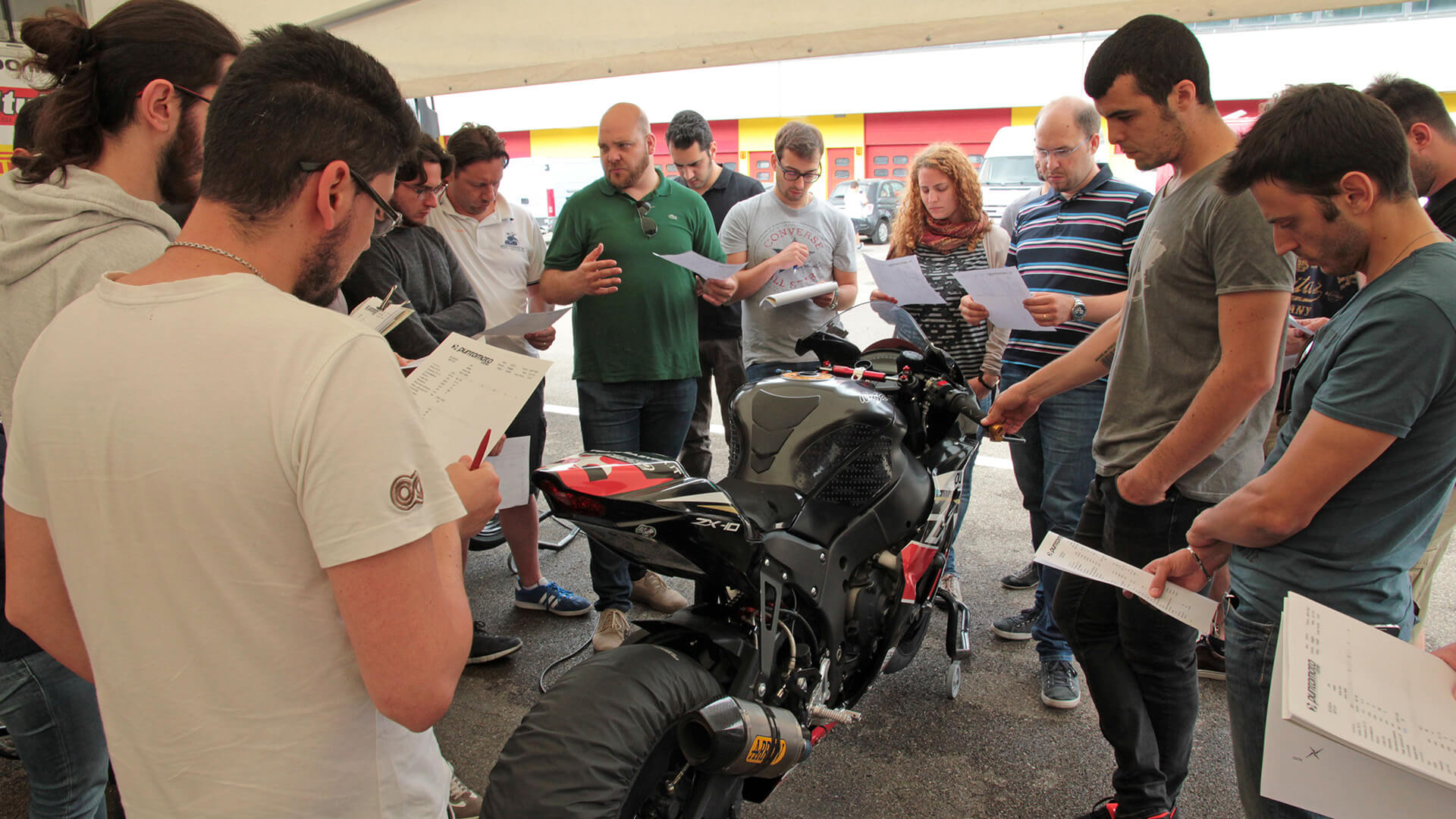 lecturer with students to race motorcycles observing a sheet with notes on telemetry