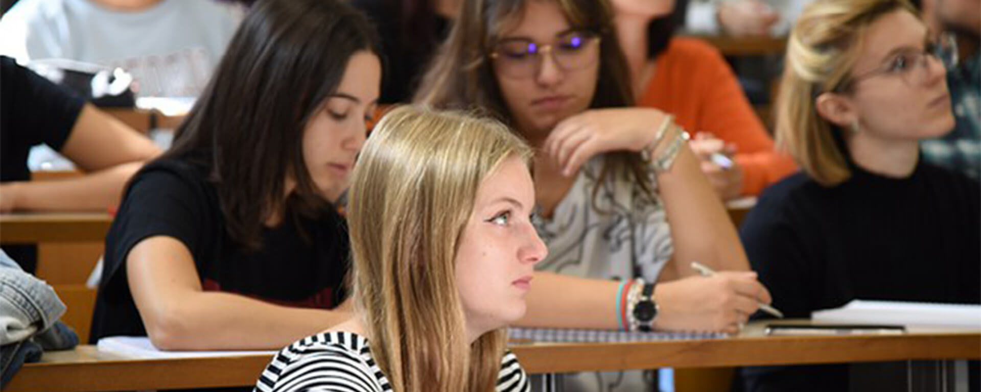 Young blonde girl attending a lecture at university