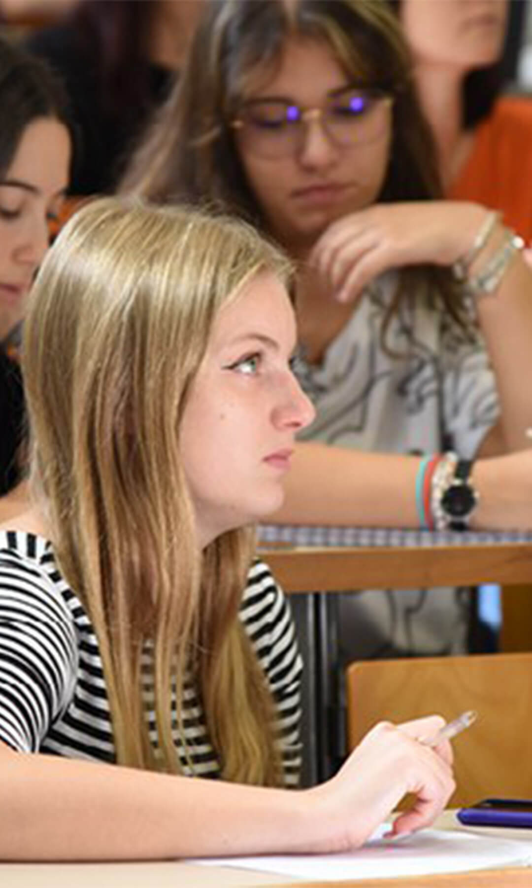 Young blonde girl attending a lecture at university