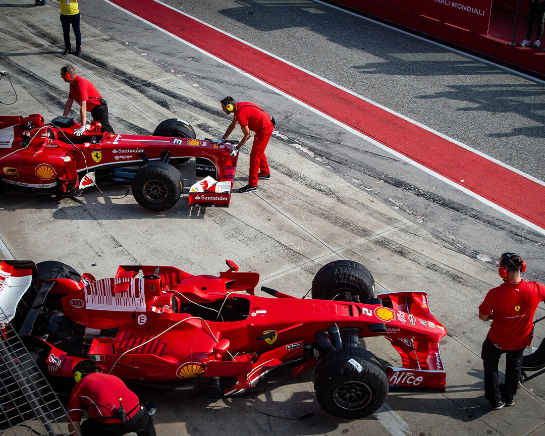 Due monoposto ferrari che vengono preparate dai meccanici nella pitlane del circuito dell'autodromo enzo e dino ferrari