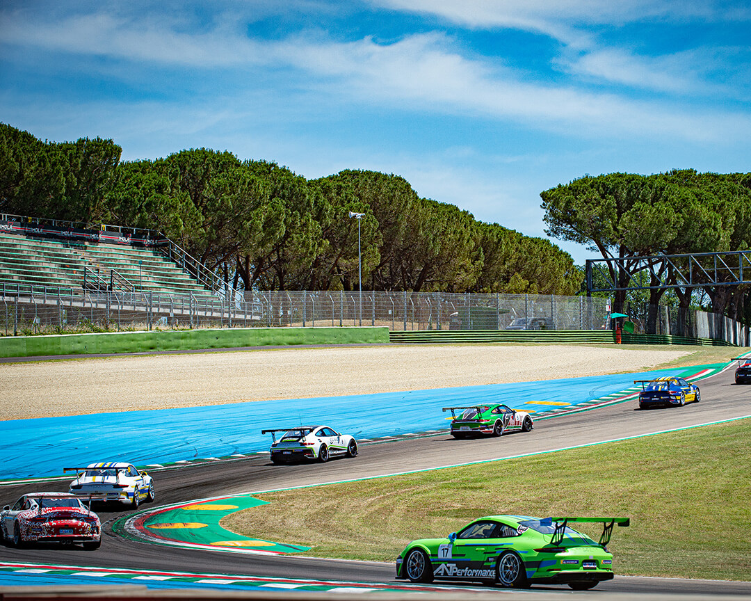 Una serie di porche da corsa che percorrono una sezione del circuito dell'autodromo enzo e dino ferrari