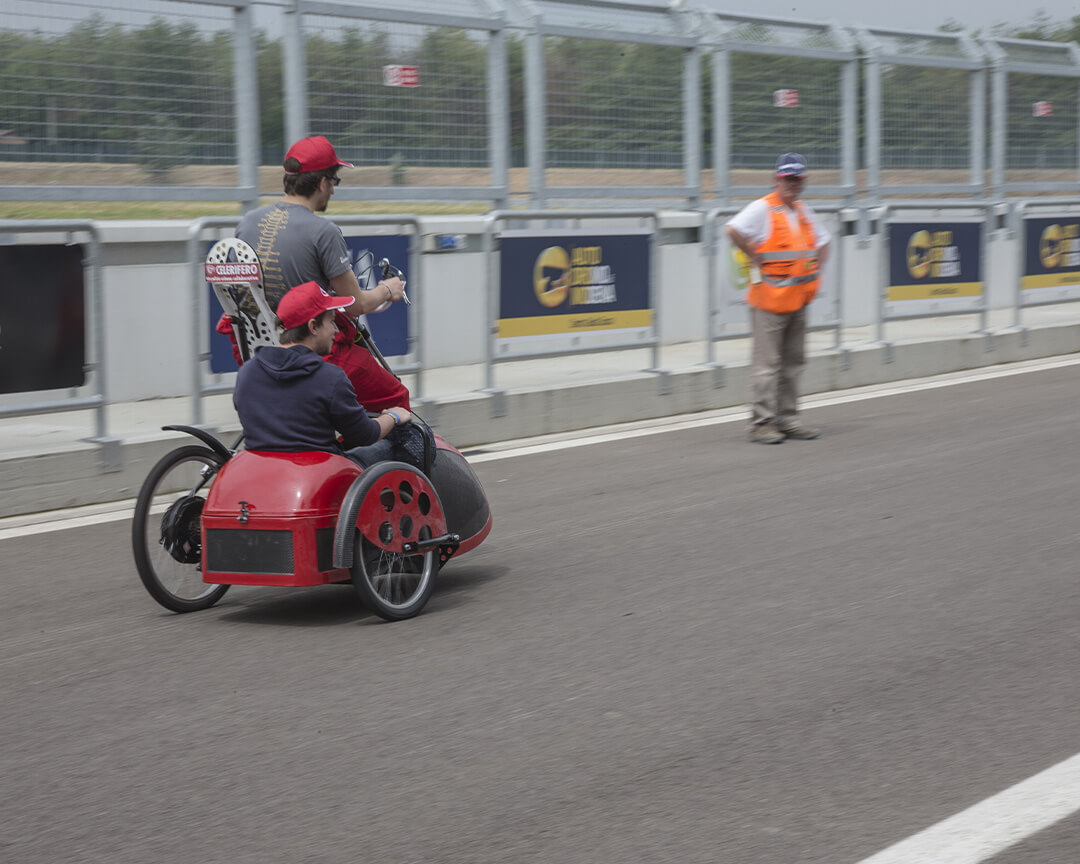Un sidecar rosso con pilota e passeggero che percorre l'autodromo di modena