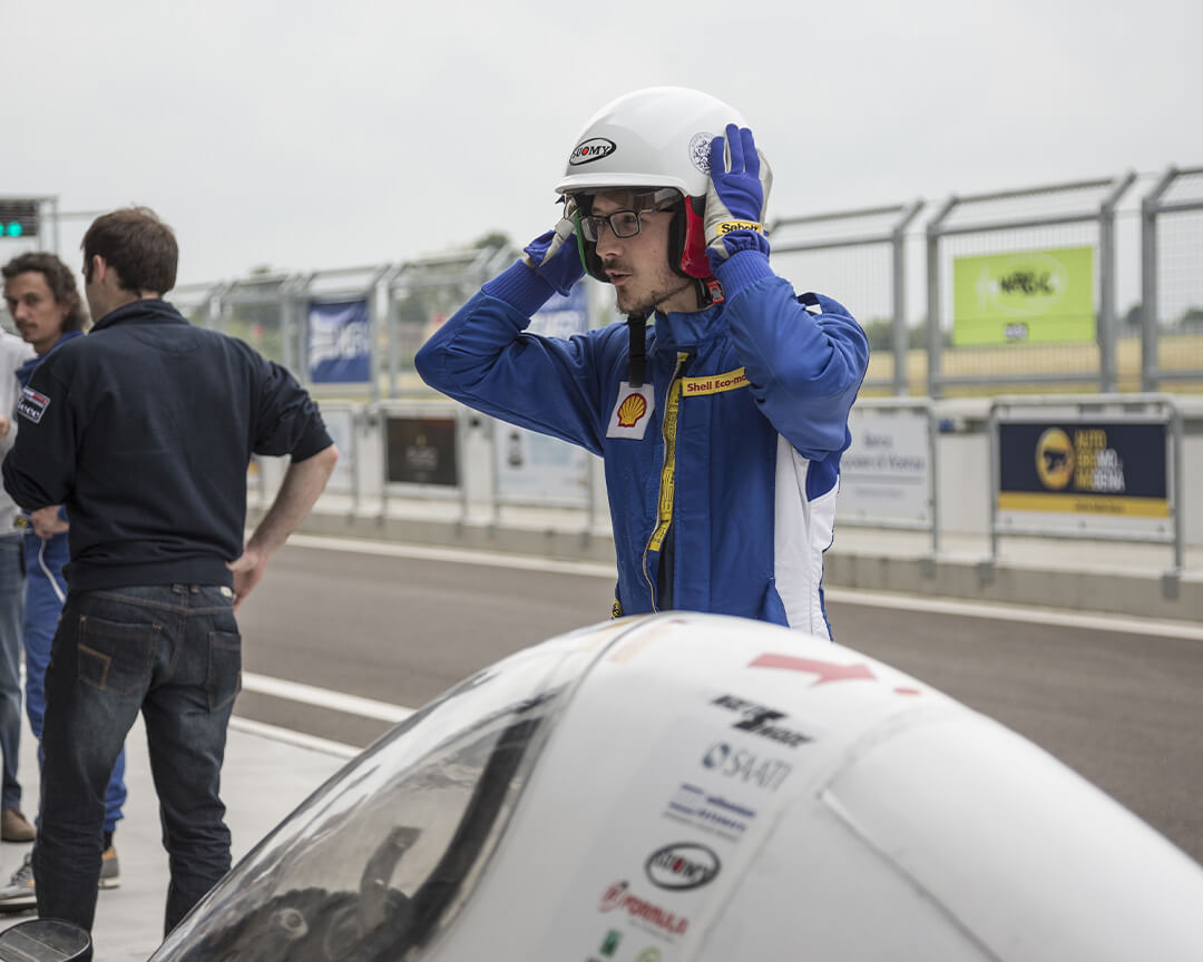 un pilota con il casco in testa davanti ad una vettura dentro l'autodromo di modena