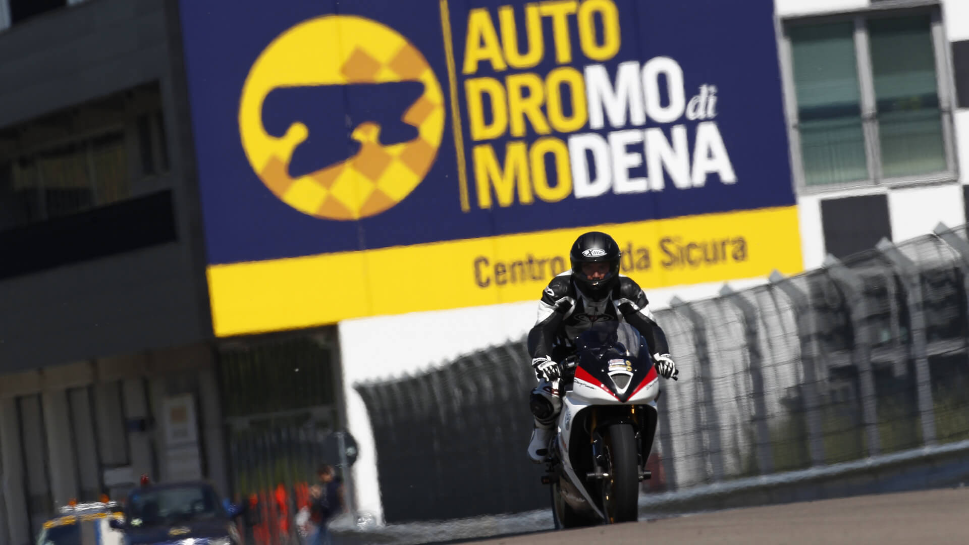 Un motociclista in sella ad una moto da pista percorre il circuito dell'autodromo di modena