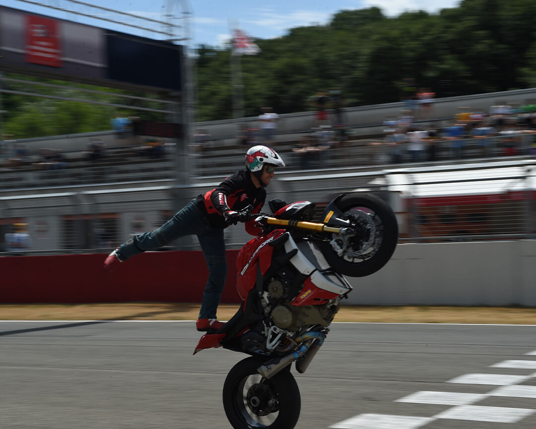 Un pilota freestyle di moto con una stradale V4 impenna sul rettilineo  dell'autodromo di varano