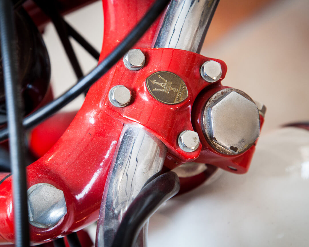 targhetta con logo Maserati incastonata in un pezzo rosso di una moto d'epoca