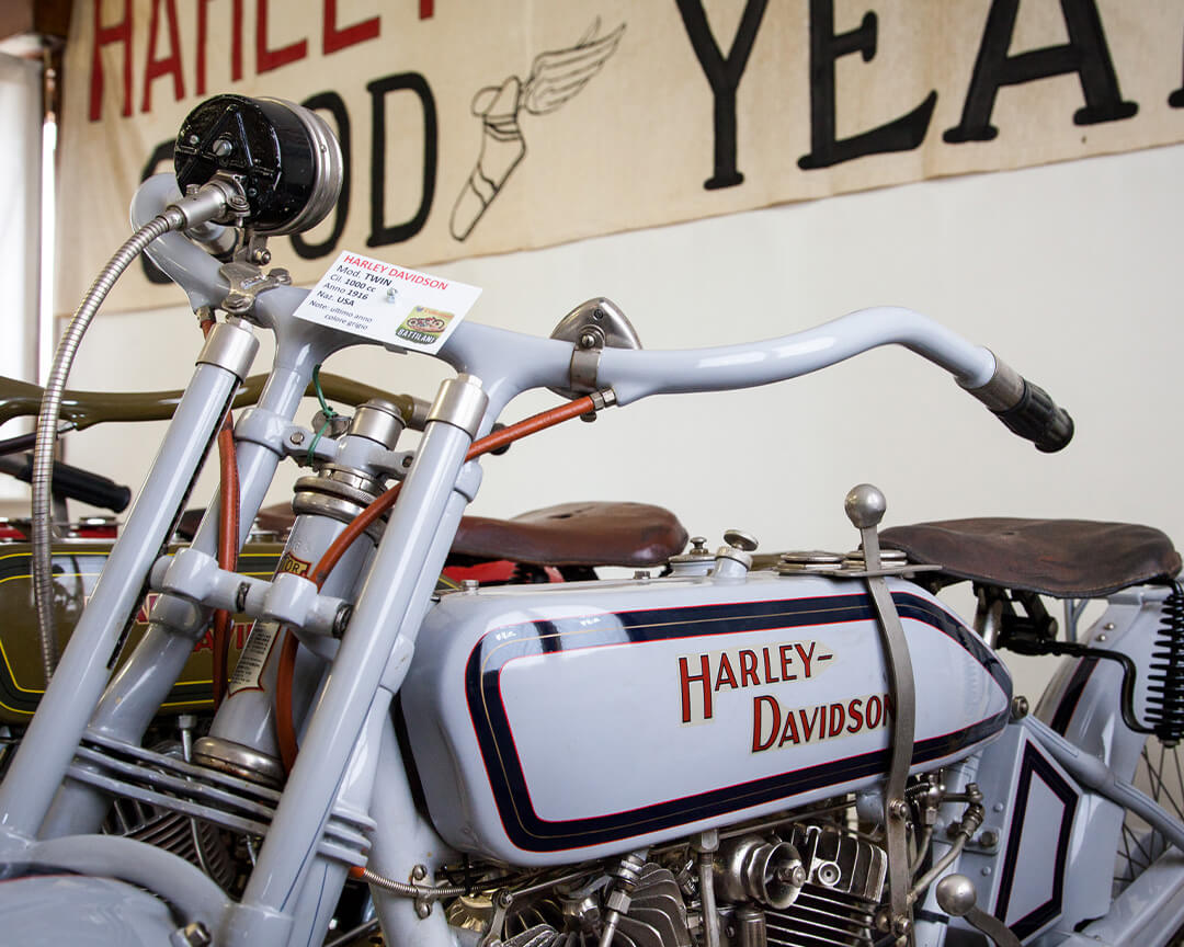Vista laterale di una antica harley davidson bianca del 1916, la moto è all'interno della collezione battilani