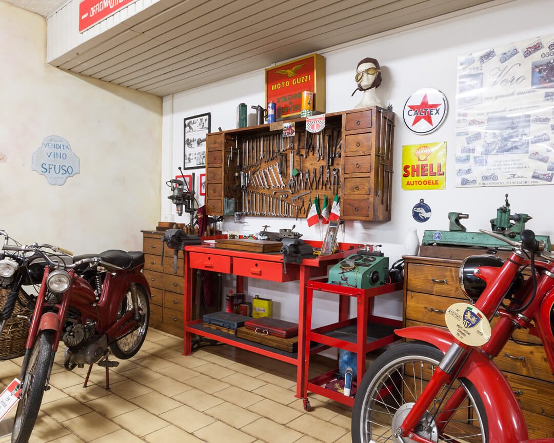 motorcycles from the guzzi collection displayed next to work tools such as wrenches and chests of drawers with motorcycle care items