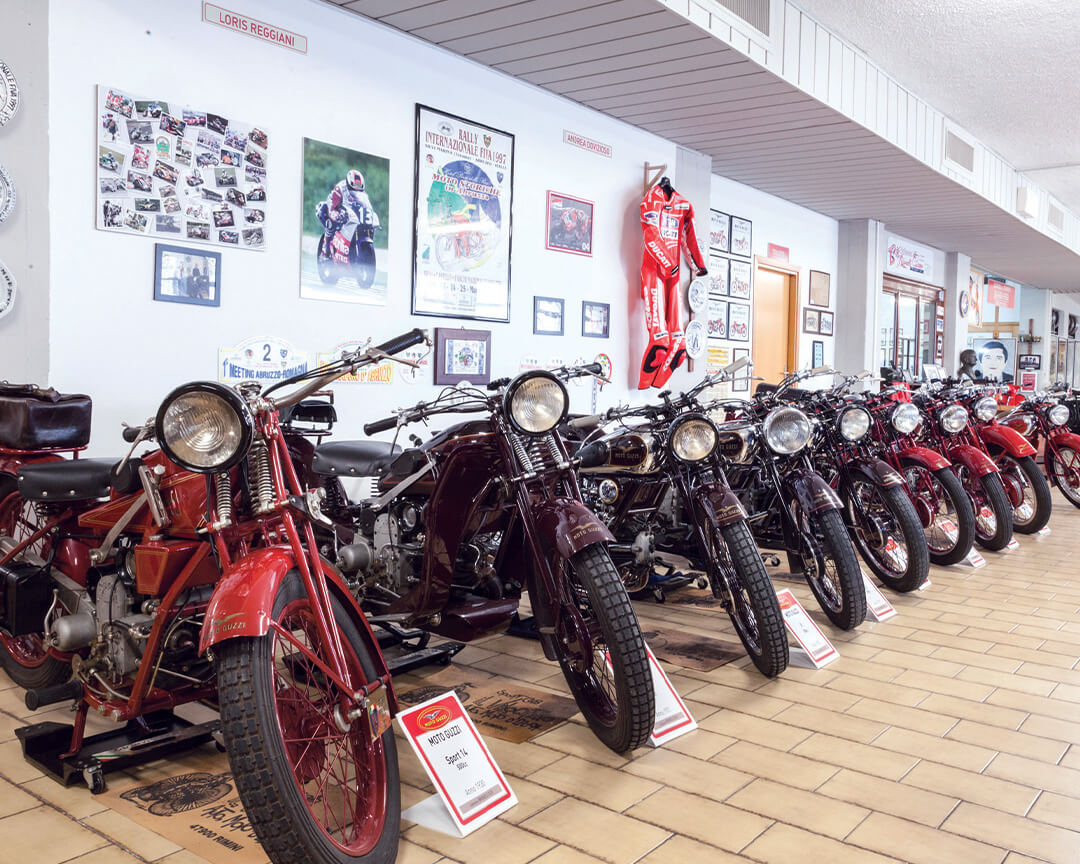 motorcycles from the guzzi collection parked in a row. hanging pictures of riders and a red Ducati suit