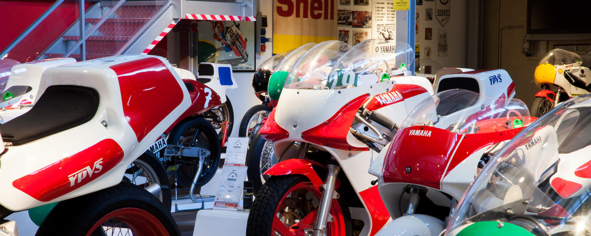 A series of historic racing Yamahas, with red and white paintwork, within the motorbike collection rests