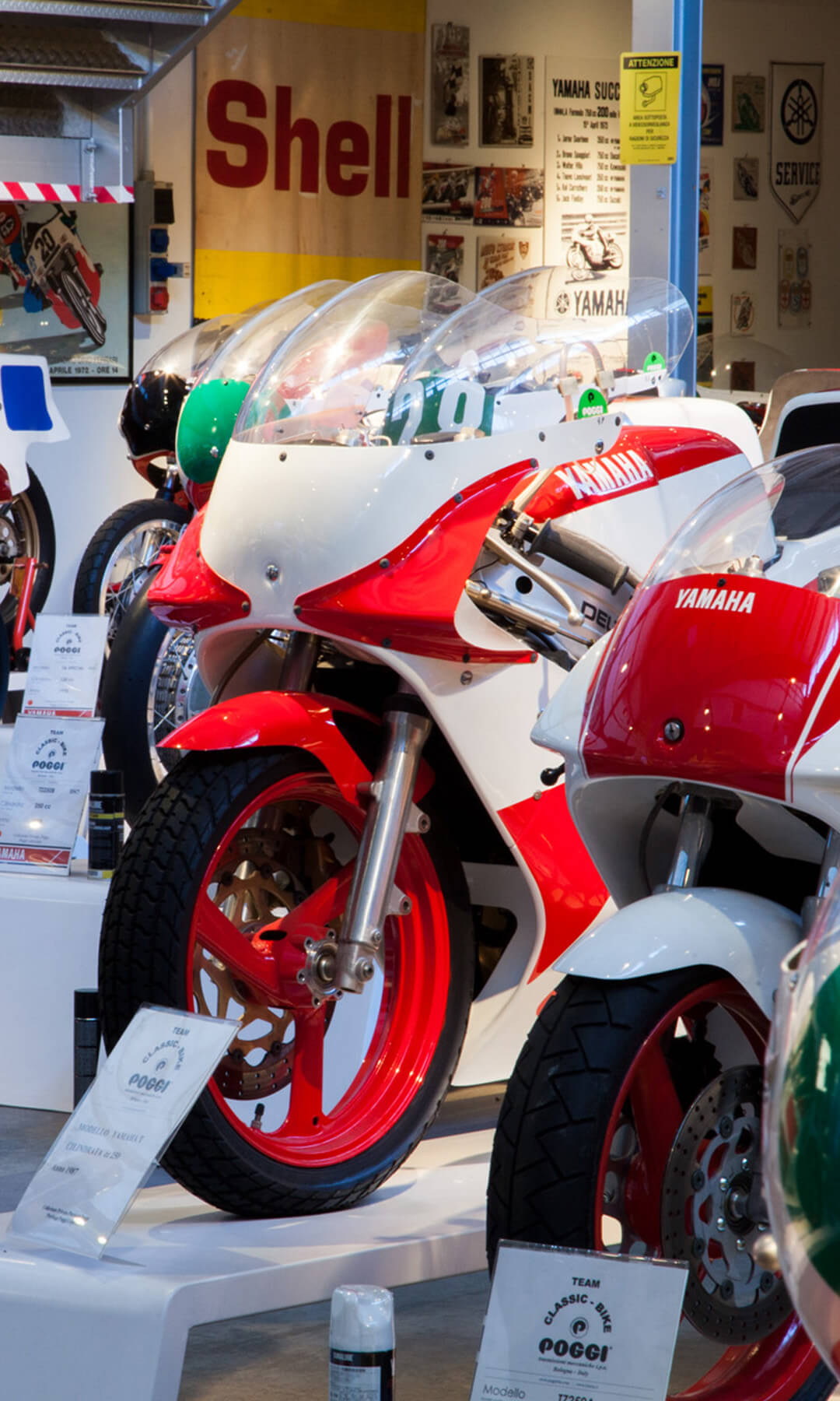 A series of historic racing Yamahas, with red and white paintwork, within the motorbike collection rests