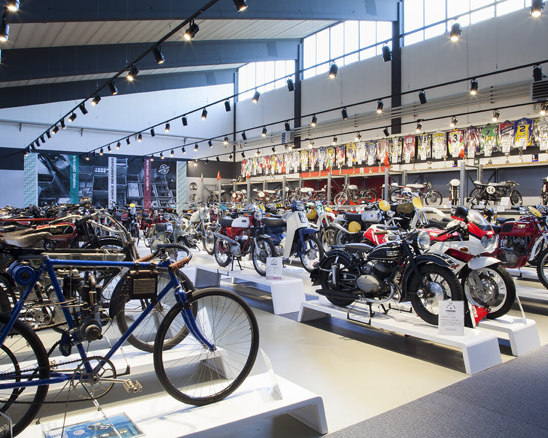 In one room of the poggi collection, bikes, motorbikes, and collector's racing bikes, part of the yamaha history, are displayed. On the walls hang motorbike suits of yamaha riders