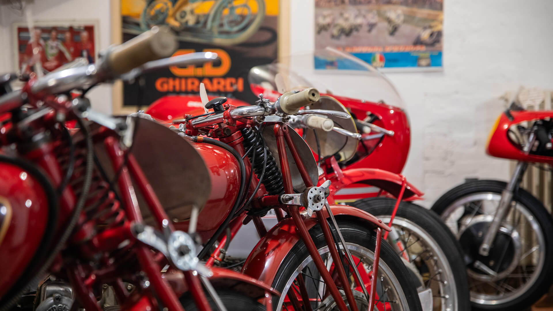 A series of red collectible motorcycles, side by side inside the Parmeggiani Collection exhibition hall