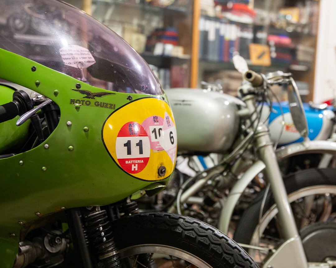 front detail of a green guzzi motorcycle within the Parmeggiani collection, with many other vintage motorcycles alongside