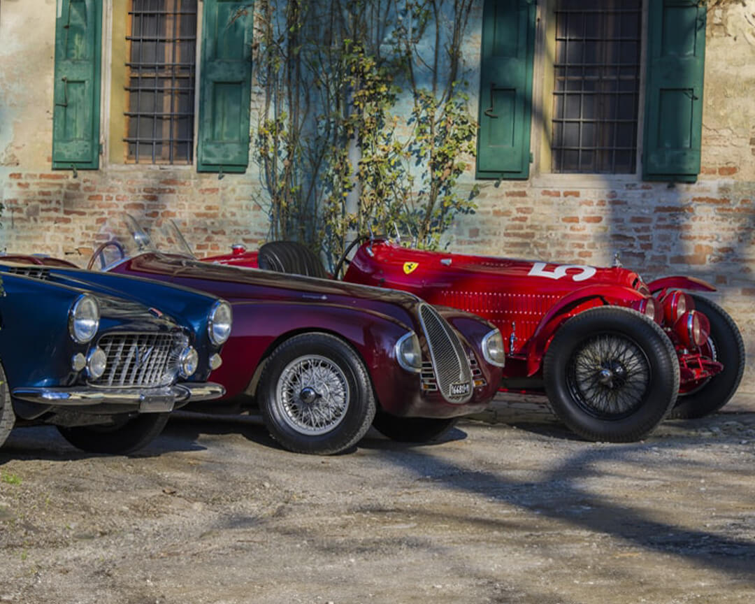 Three vintage cars from the righini collection parked side by side in front of a brick structure