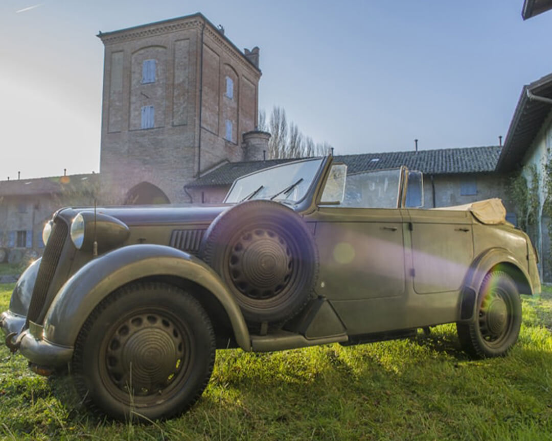 Off-road vintage military green convertible from the righini collection, parked in the courtyard of an old estate on a sunny day