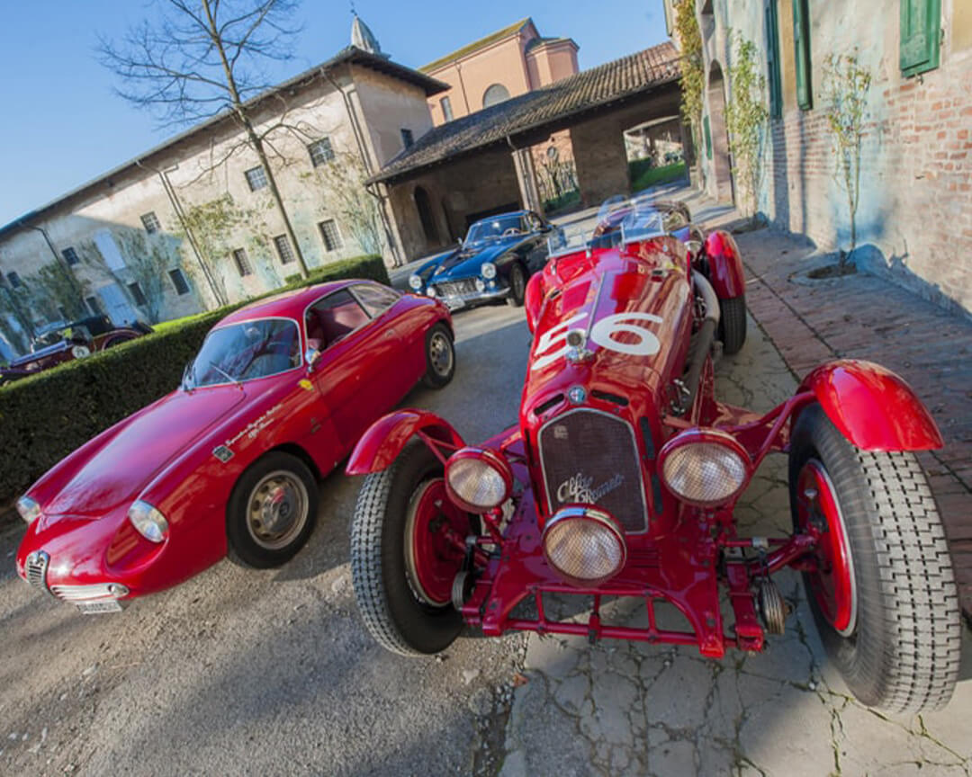 four vintage sports cars from the righini collection parked inside the courtyard of a villa