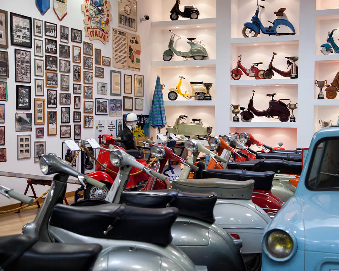 room with multiple piaggio vespas and paintings and a piaggio car
