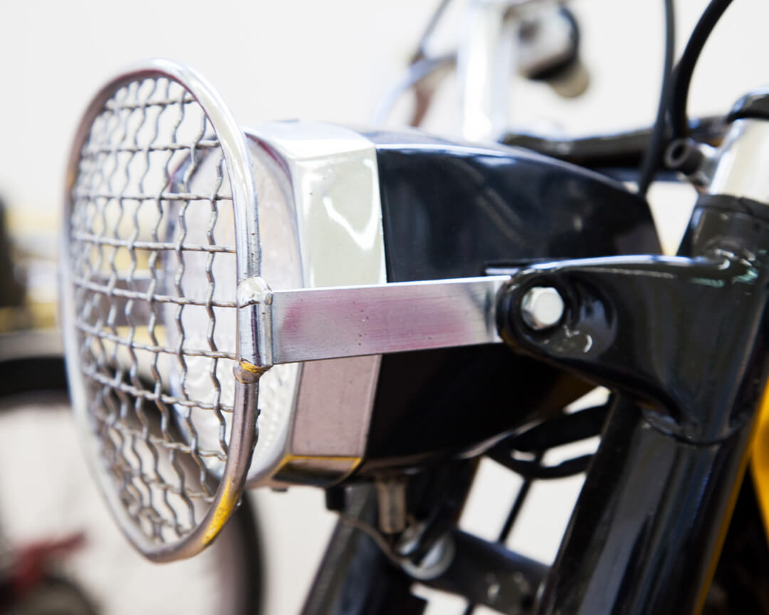 Dettaglio di un faro con griglia di protezione, di una moto all'interno del museo Demm