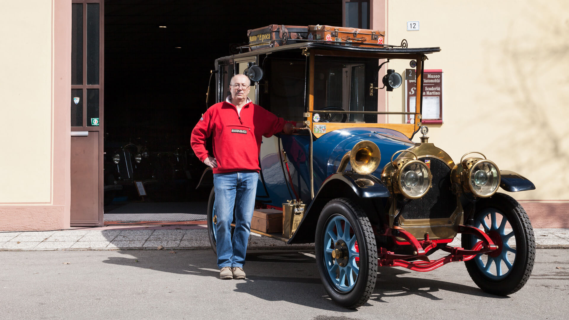 Roberto Vellani president of the scuderia san martino standing next to a collector's car, outside the scuderia's headquarters