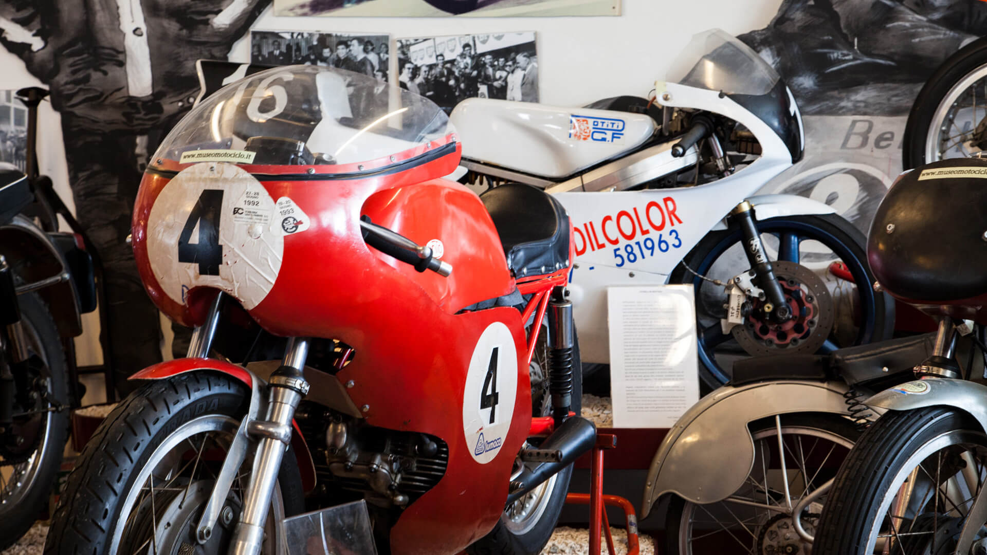 in the foreground a vintage racing motorbike with the number 4 among other collector's bikes in the national motorbike museum