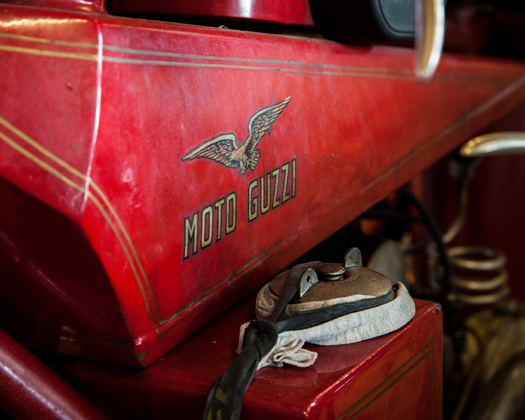Detail of the Moto Guzzi logo on a red fairing of a vintage motorbike, part of the National Motorcycle Museum