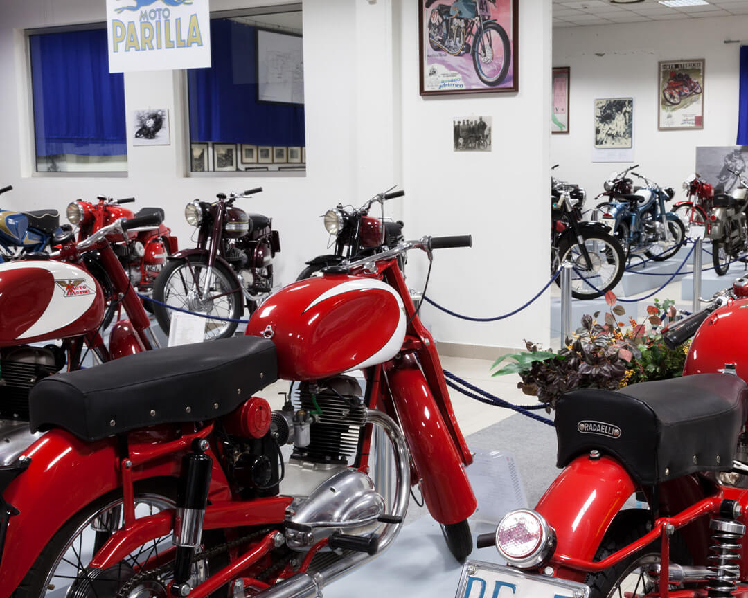 Rear view of two red morini motorbikes, among many other vintage motorbikes, inside the bariaschi motorbike museum