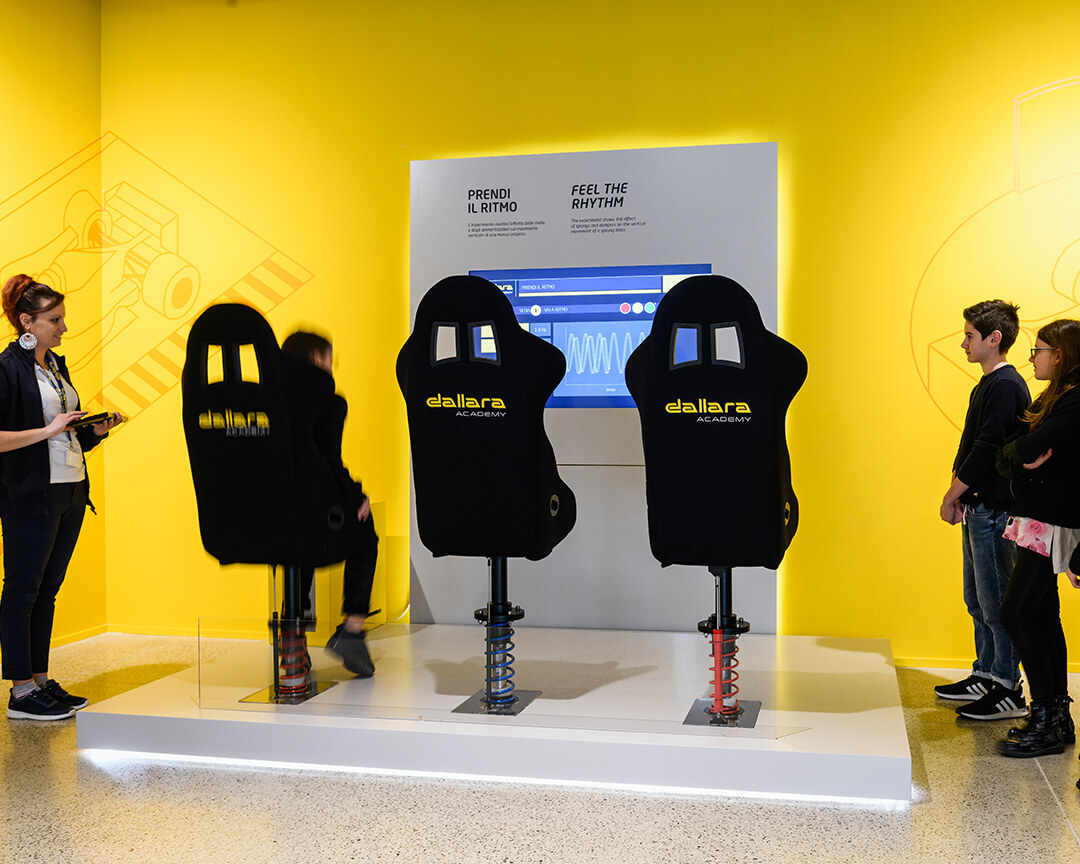 Take the Rhythm' game for kids at the Dallara Museum. There are 3 chairs with springs that move, other children at the side a lady with a tablet