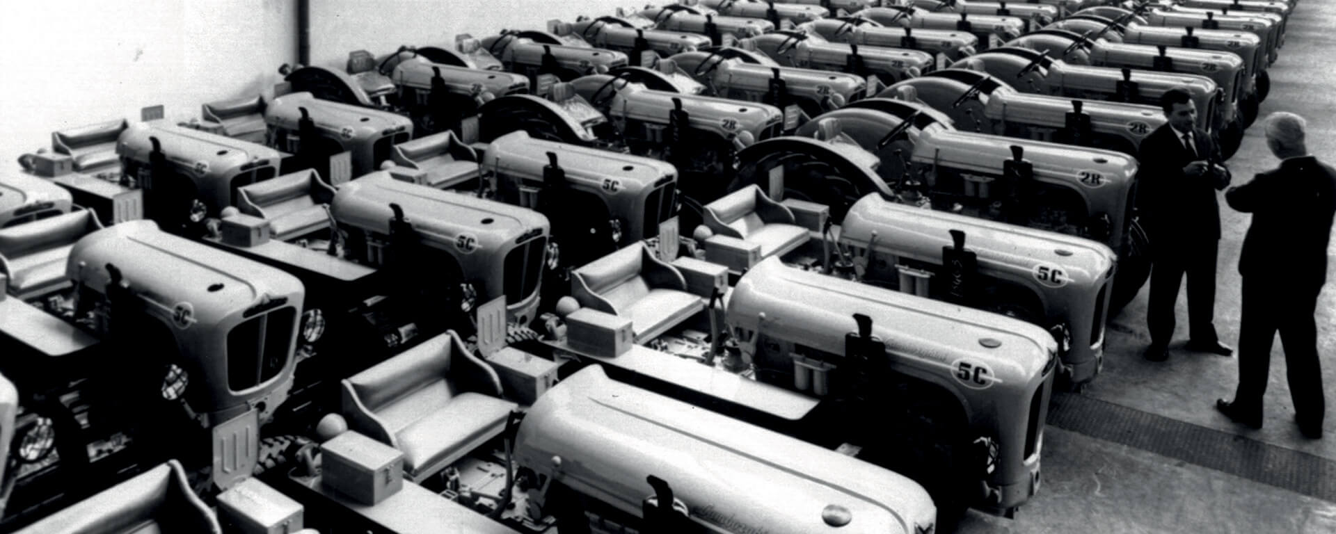 Black and white photos of Lamborghini tractors inside the factory, parked side by side