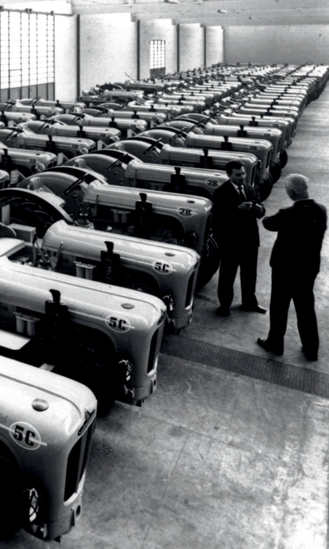 Black and white photos of Lamborghini tractors inside the factory, parked side by side