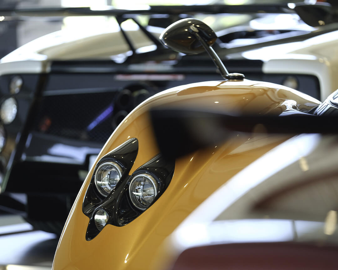 dettaglio su fanale a doppio proiettore di una Pagani Huayra gialla esposta al museo
