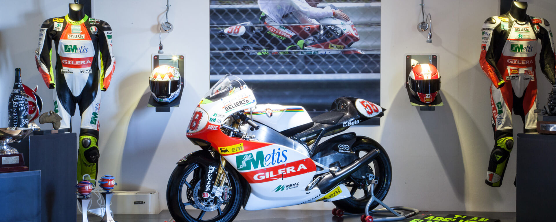 in primo piano moto numero 58, dietro due caschi e tute da corse di moto di Marco Simoncelli