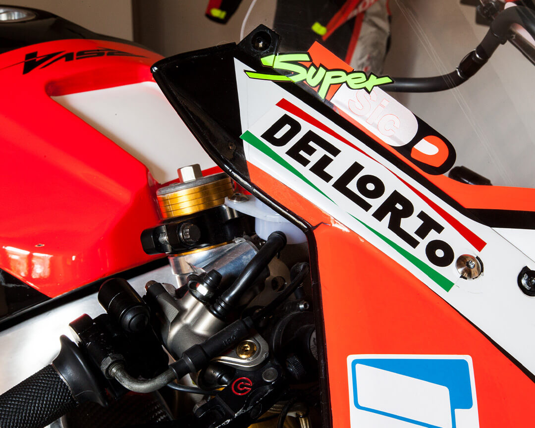 Dettaglio logo Dellorto con scritta sopra Super Sic e pezzo di motore della moto