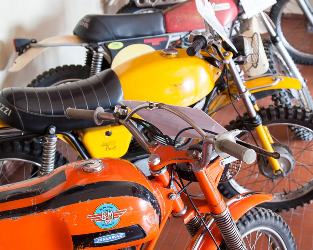 Handlebars and tank of an orange and black bonvicini motorcycle on display at the motorcycle museum in scortichino