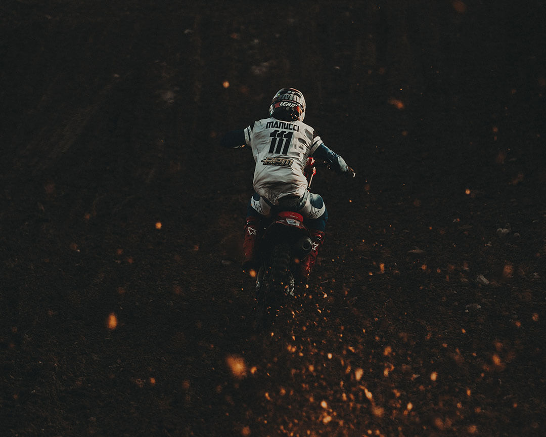 view from behind of motocross rider Mannucci number 111 on black background