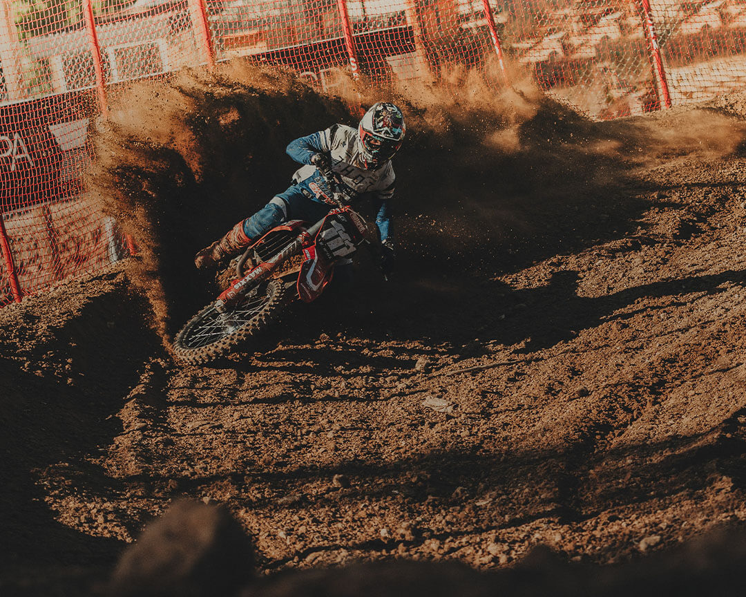 motocross rider making a turn with soil of the path that rises around him