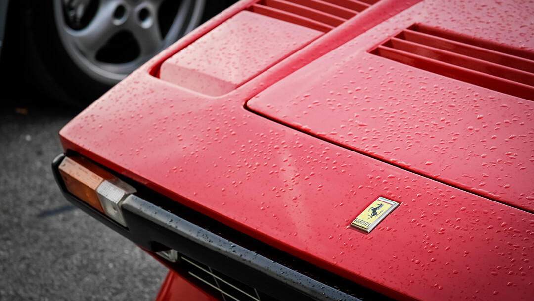 detail of a vintage red ferrari with water drops