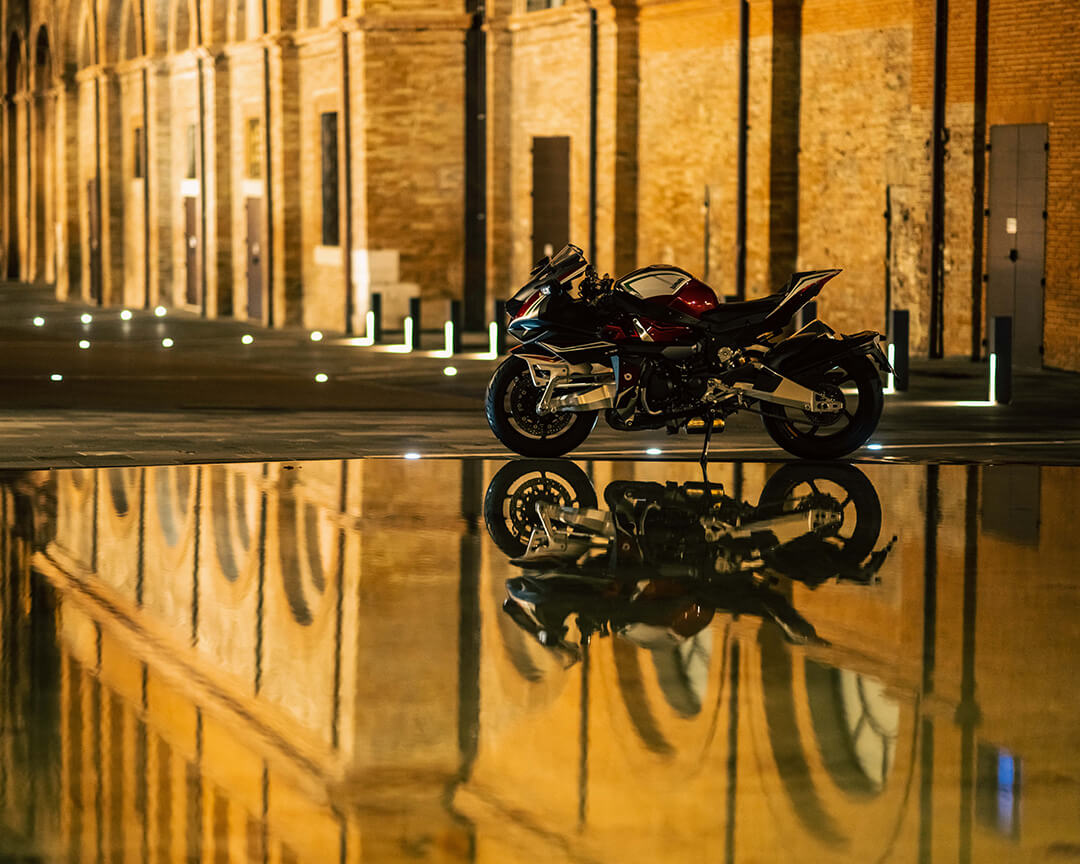 black Bimota motorbike parked outside with reflection on the water