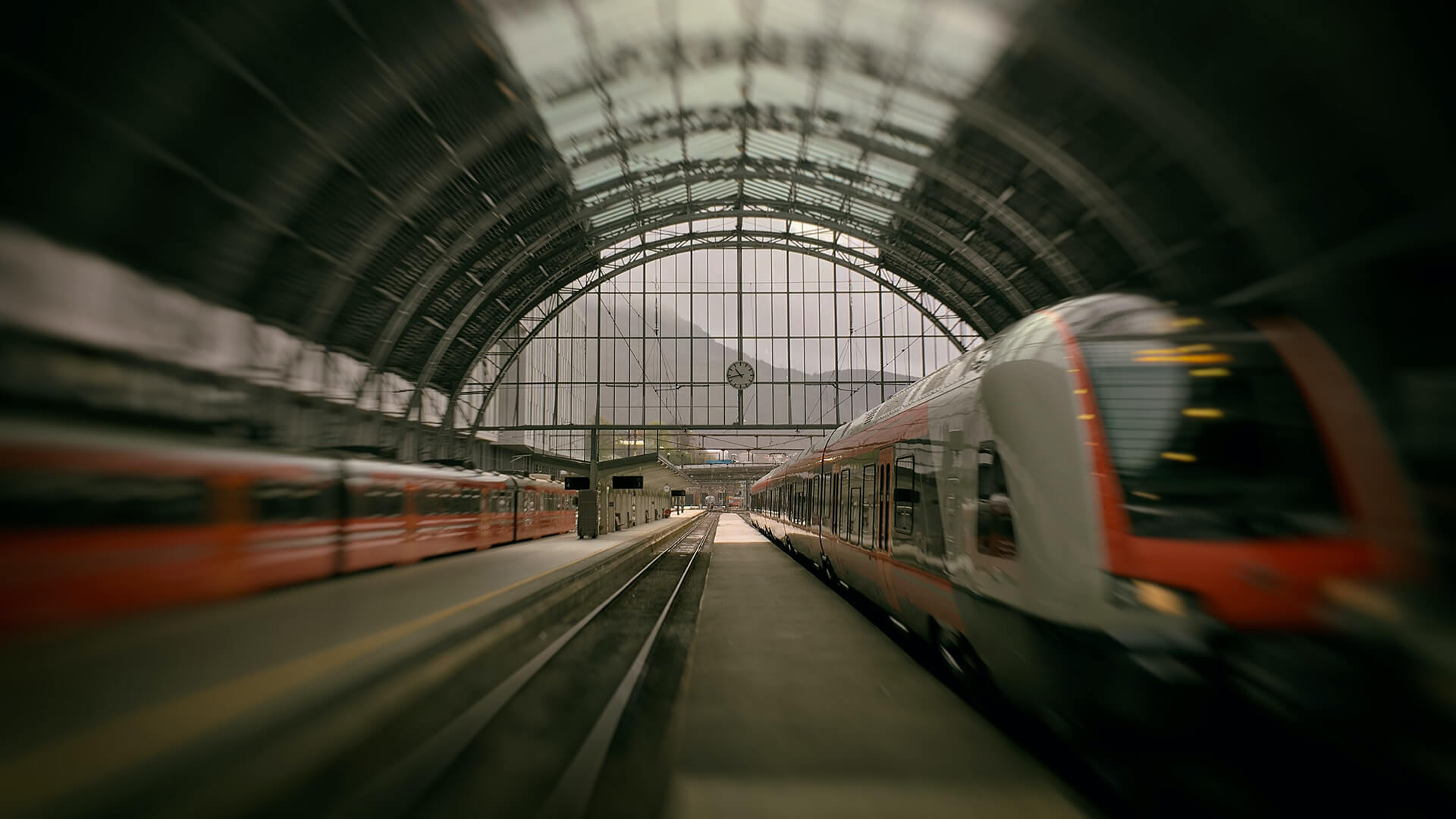 Interno di una grande stazione ferroviaria con un tetto a volta in vetro e acciaio.
