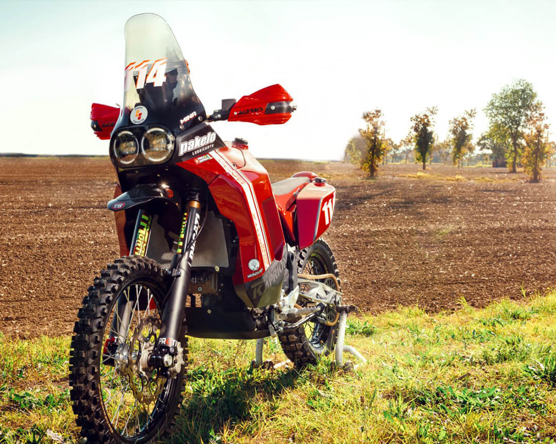 vista semi frontale di moto maxi enduro elaborata da Engine engineering su una lingua di erba davanti ad un campo