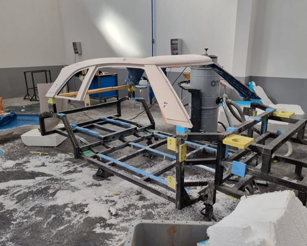 Chassis of a car being processed, inside an FD Group workshop filled with tools and materials