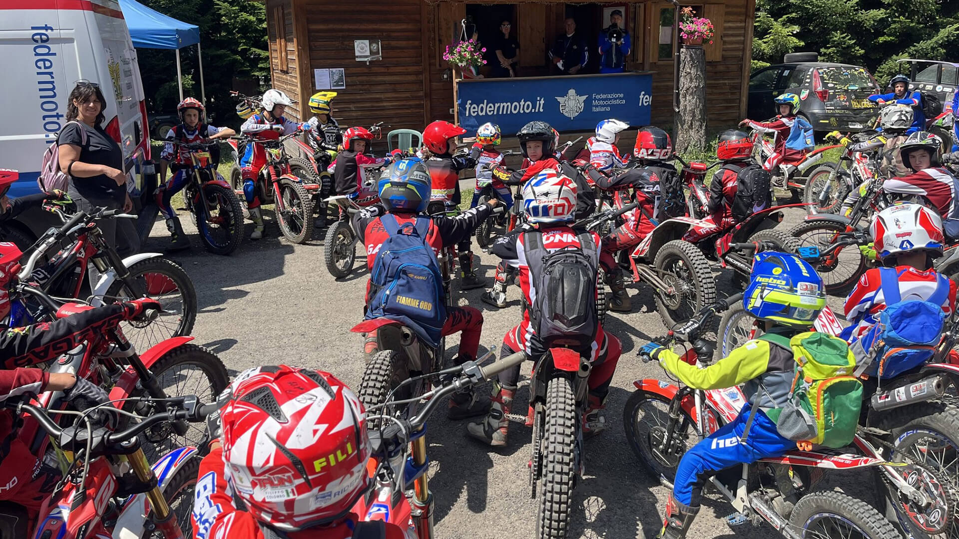 A large group of young people from the Federazione Motociclistica Italiana gathered in front of the FMI booth, riding their trials bikes.