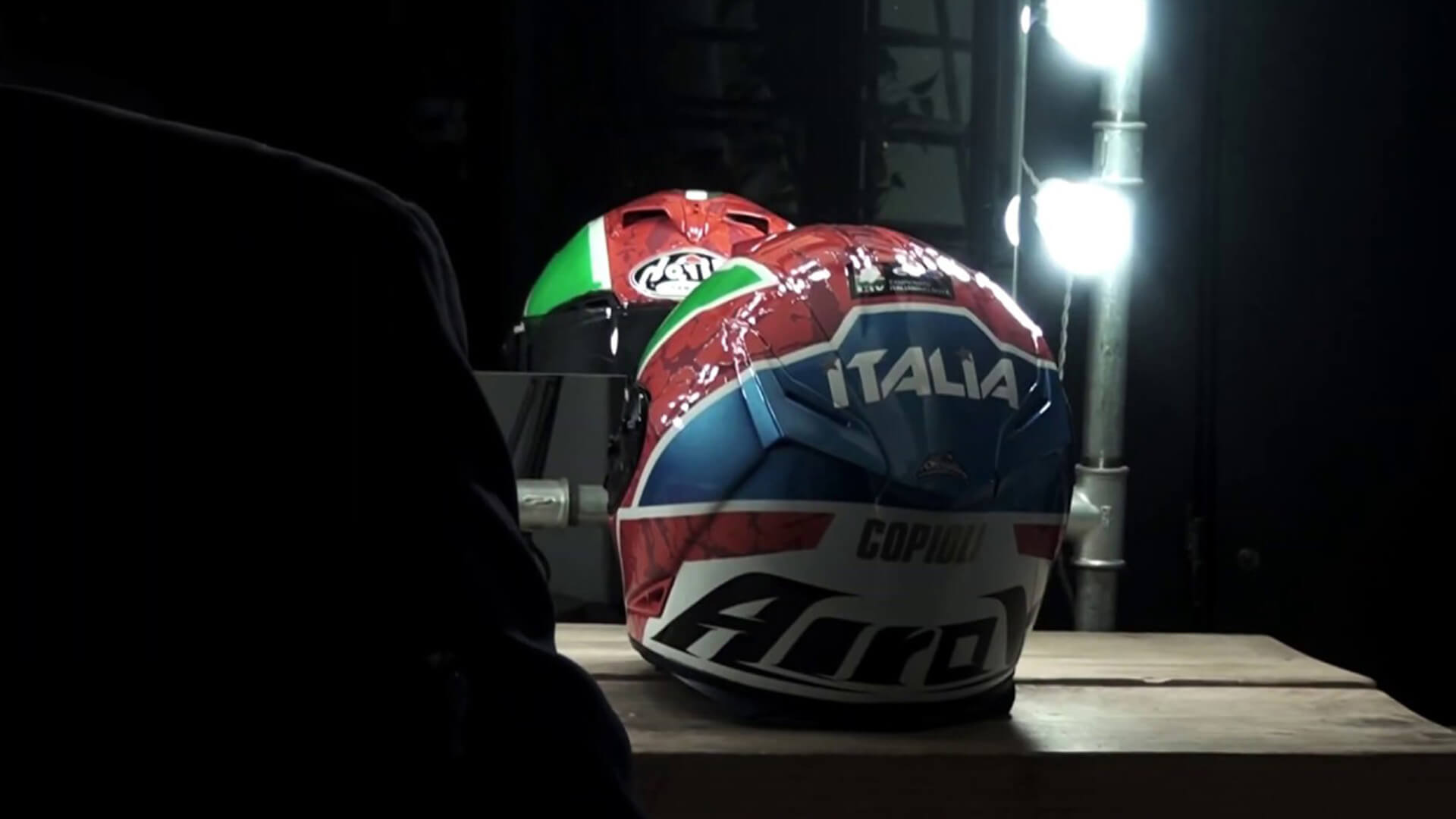 Motorcycle helmet of the Italian Motorcycle Federation, red blue, white and green, with the word italy in the foreground, resting on top of a table in front of a mirror