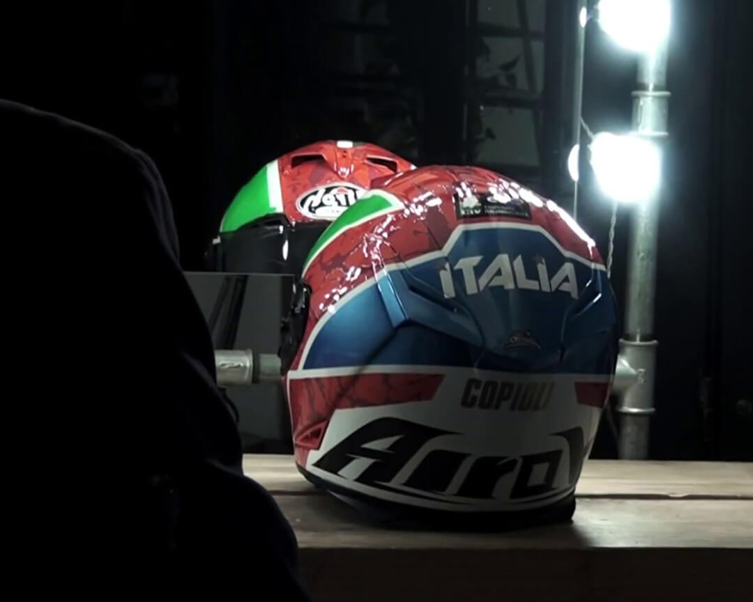 Motorcycle helmet of the Italian Motorcycle Federation, red blue, white and green, with the word italy in the foreground, resting on top of a table in front of a mirror