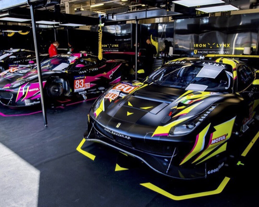 Three Ferrari Iron Lynx from the Endurance Championship , positioned in the pits ready to be prepared for the race.
