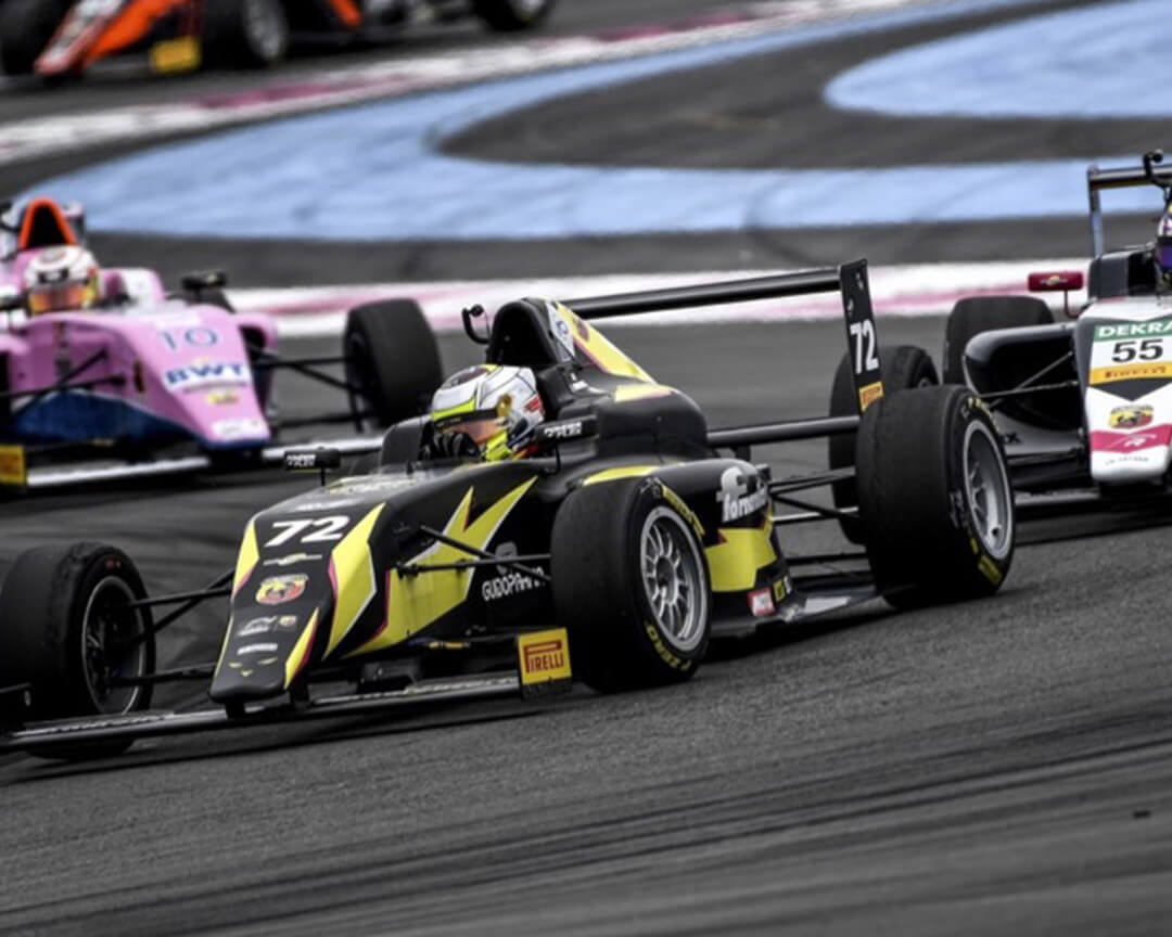 Three single-seaters racing each other as they negotiate a curve.