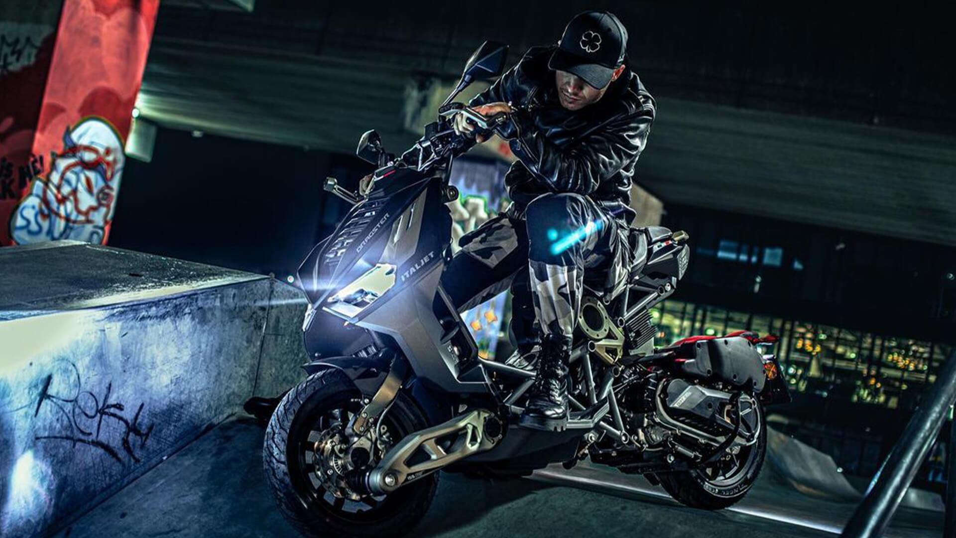 An Italjet motorcycle with headlights on, frame exposed and engine modifications is photographed on a ramp.