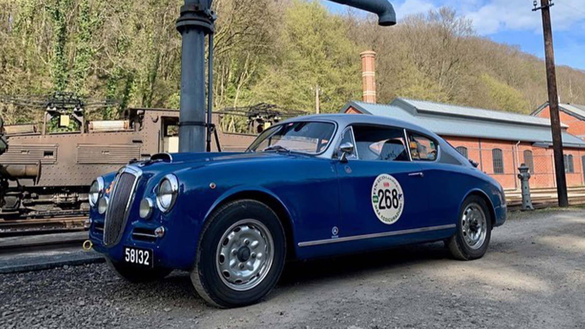 Blue vintage car with silver roof with number 268 on driver's side door parked outside