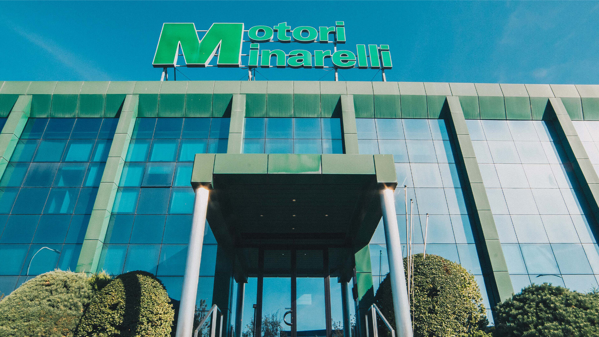 Main facade of motori minarelli headquarters, with the green logo, Motori minarelli, on top of the glass building